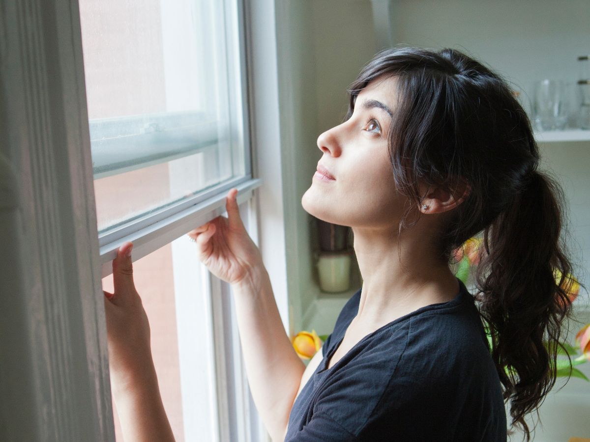 1 Side-view-of-woman-opening-window-at-home